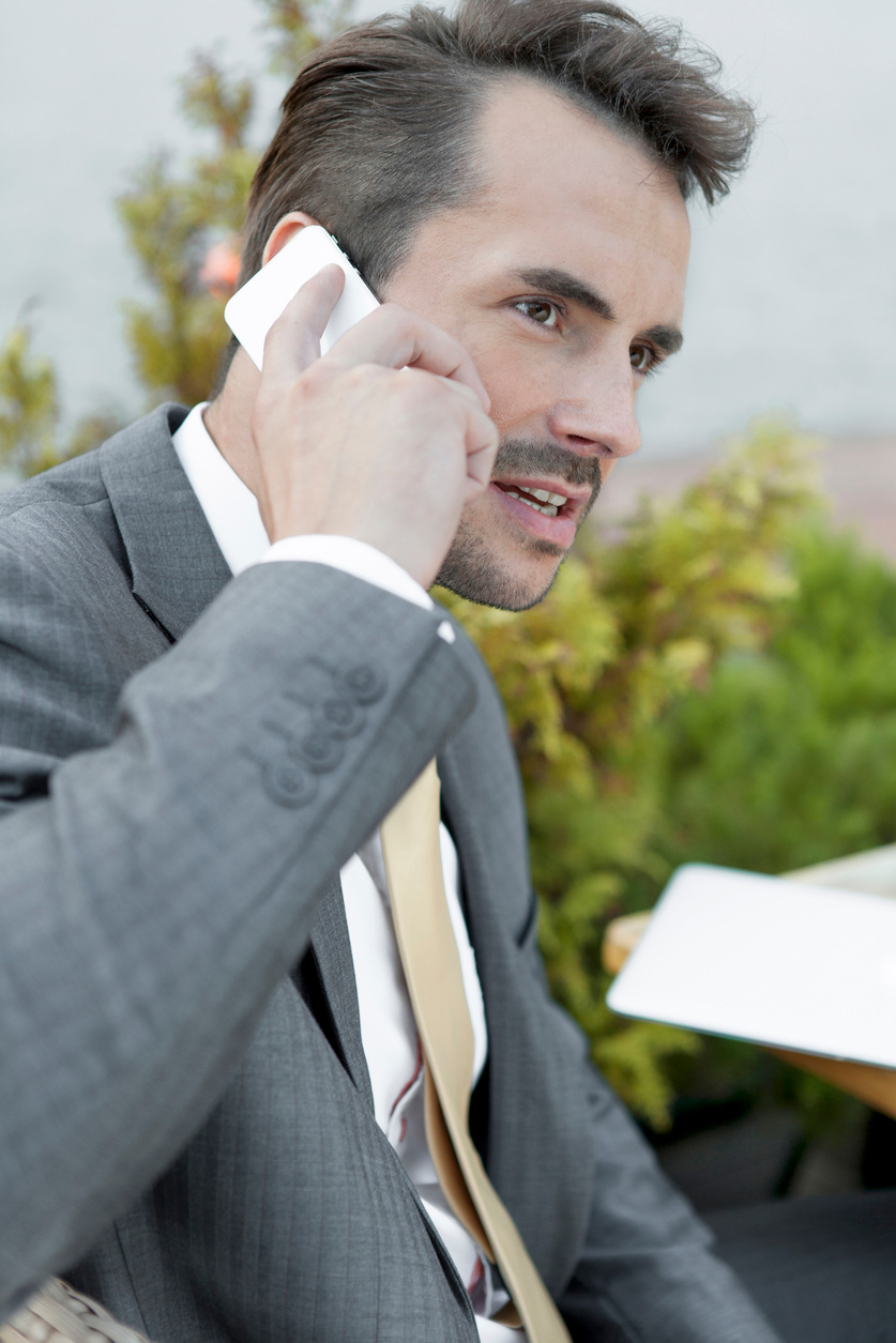 Businessman answering cell phone outdoors